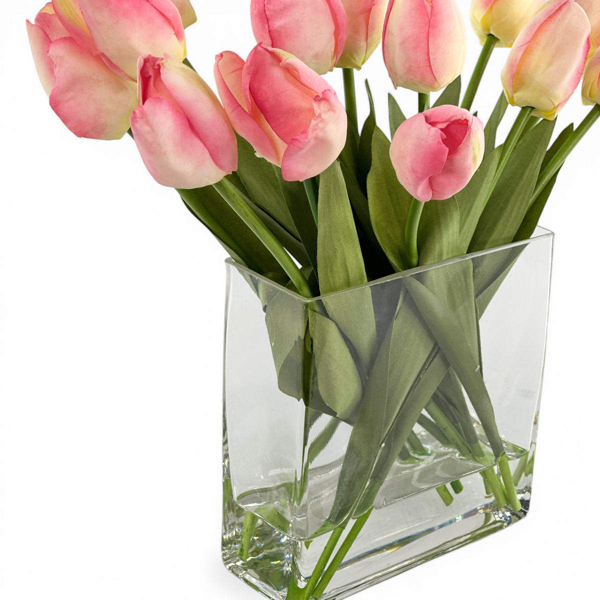 Close-up Clear glass vase with faux pink tulips on a white background