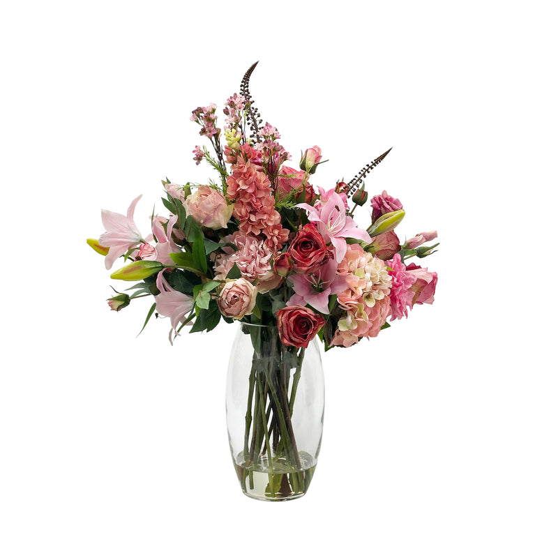 Bouquet of faux pink and red flowers in a clear vase on a white background