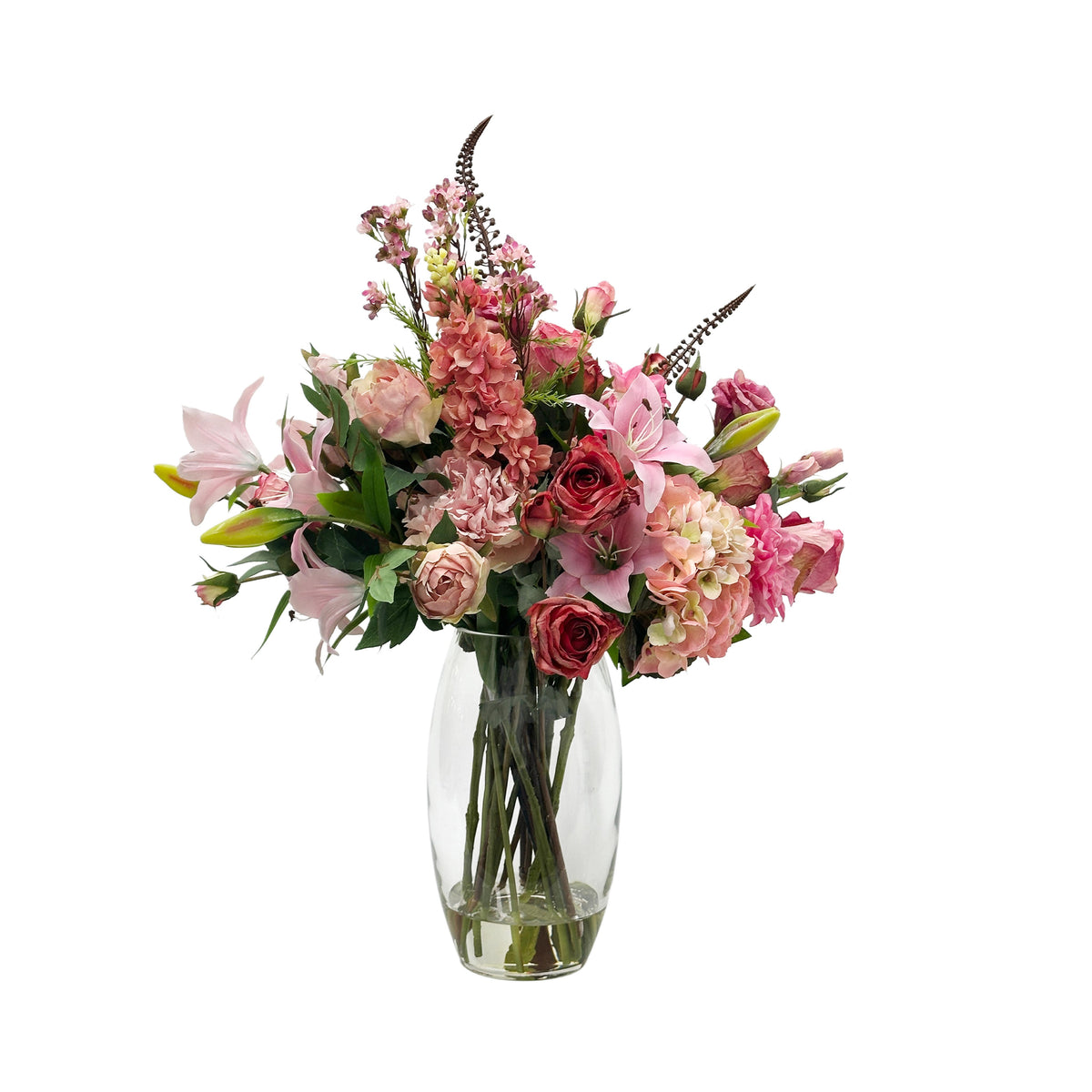 Bouquet of pink faux flowers in a clear vase on a white background