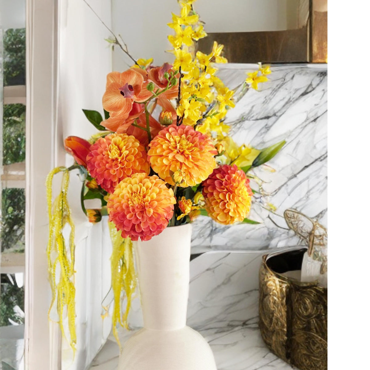 Colorful flower arrangement in a off white vase on a marble surface with a off gold container.