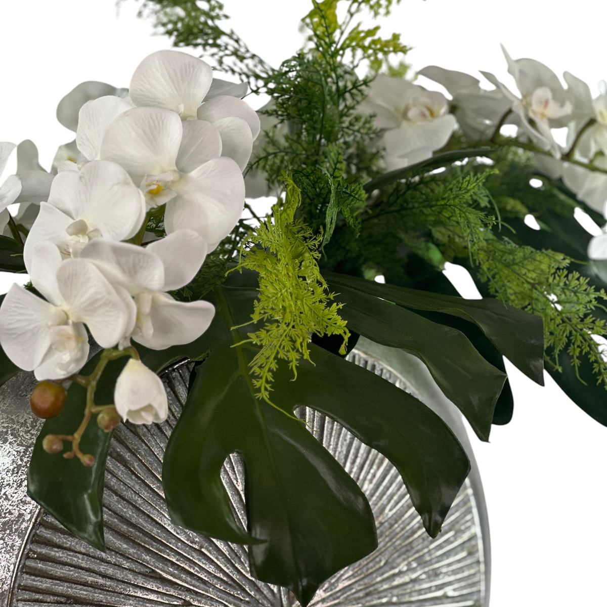 Bouquet of white orchids and green foliage on a decorative stand.