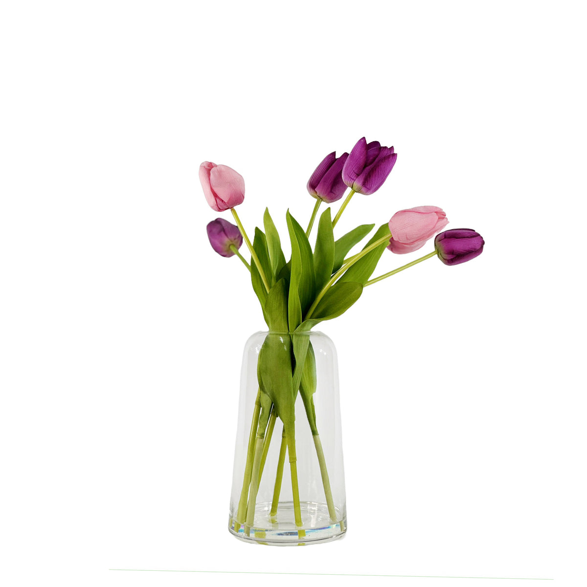 Pink and purple faux tulips in glass vase with faux water on a white background