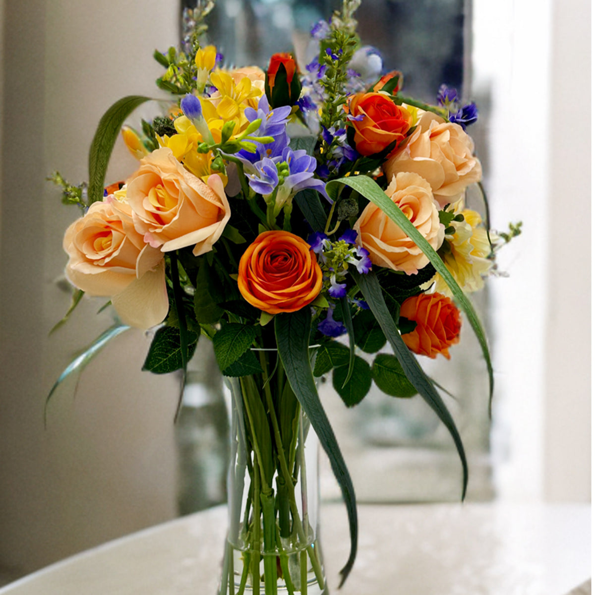 Mixed Blue and Yellow Freezia Dahlia Roses in Waisted Glass Vase