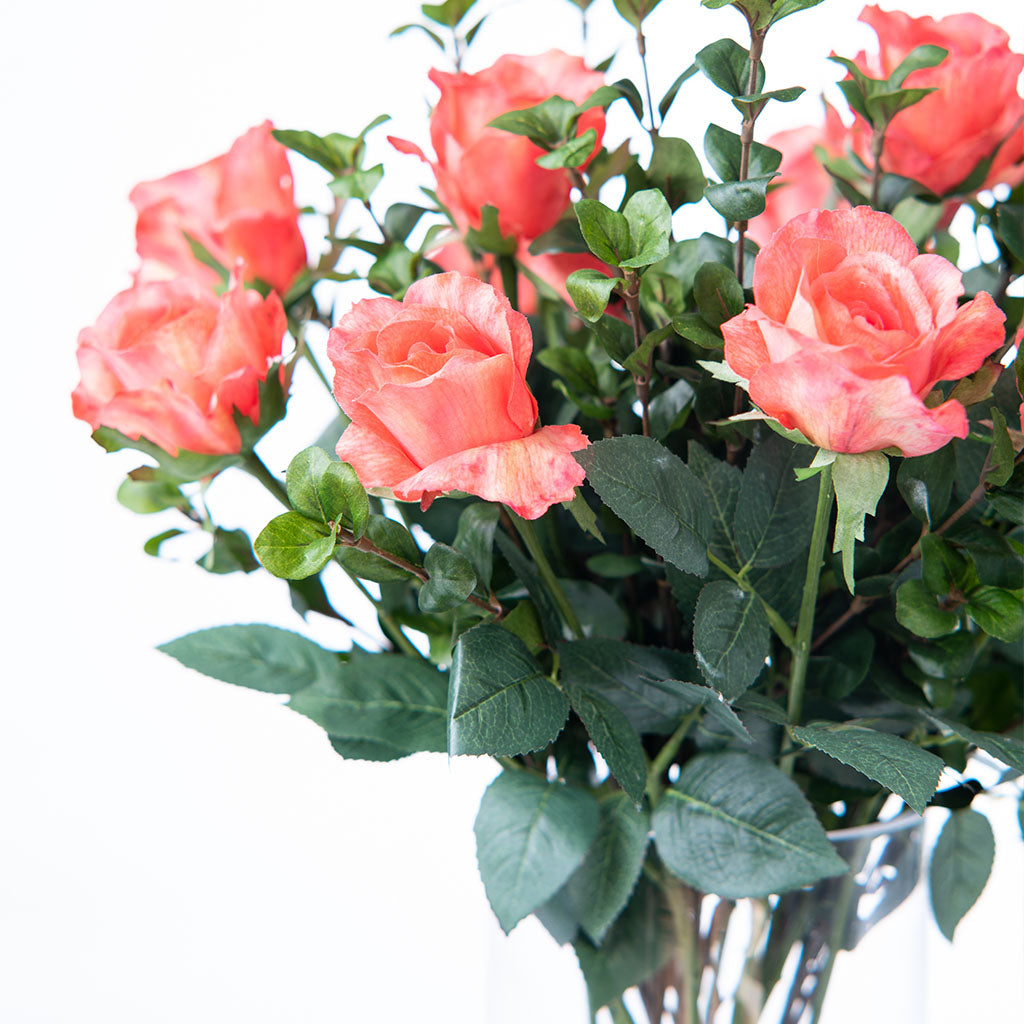 Close up of Artificial Coral Rose heads in Vase with Faux water